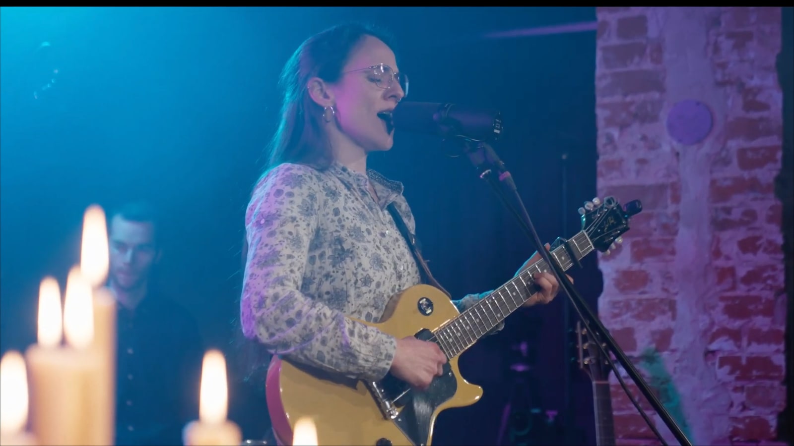 Singer and guitar from the live recording sessions with candles and colored lighting.