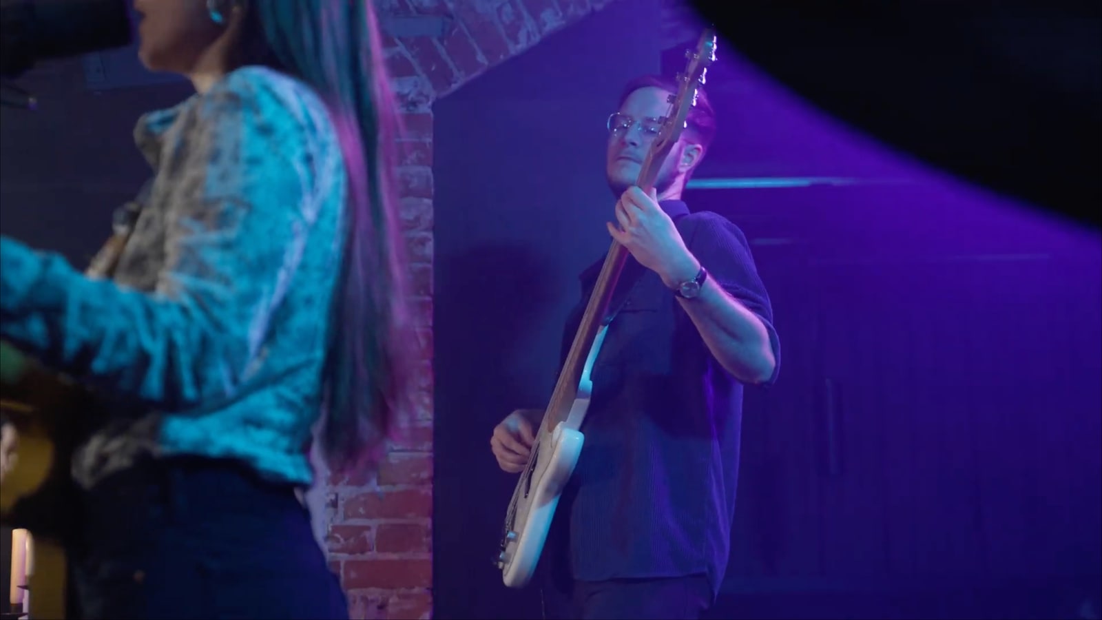 Bass and guitar moment from the music and performance sessions with magenta-cyan lighting.